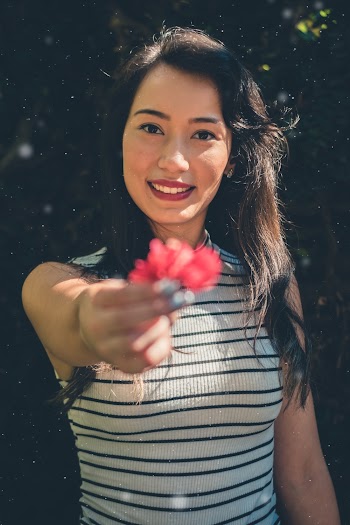 Woman In White And Black Stripe Sleeveless Shirt Holding Red Petaled Flowers While Smiling