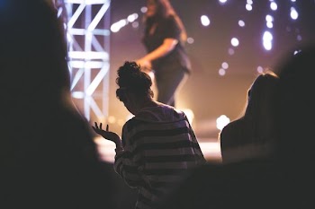 woman in white and black striped blouse beside concert stage