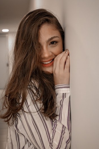 Woman in White and Black Striped Dress Shirt Leaning on  Wall