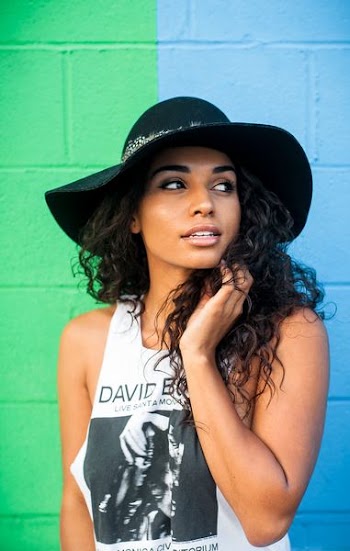 woman in white and black tank top beside green and blue painted wall