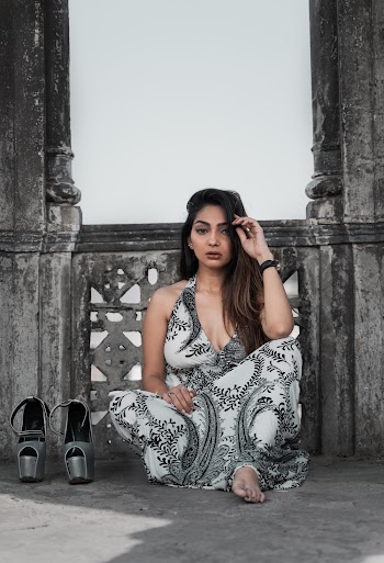 Woman in White and Blue Floral Sleeveless Dress Sitting on Concrete Wall