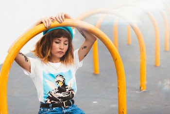 Woman In White And Blue T-shirt Sitting Under Yellow Metal Arch