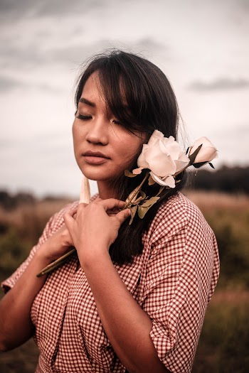 Woman In White and Red Checkered Dress Holding A Flower