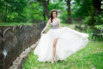 Woman in White and Silver Dress Posing Near a Fence