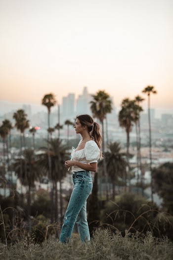 Woman in white blouse and blue jeans standing on grass field