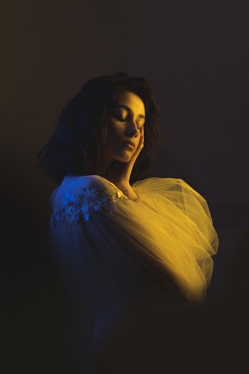 Woman in White Clothing Touching Her Face