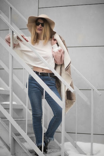 Woman in White Crew-neck Long-sleeved Crop Top and Blue Denim Fitted Jeans Outfit Standing on White Metal Stairs Beside White Wall at Daytimne