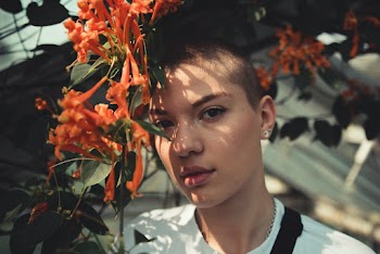 Woman in White Crew-neck Shirt Behind Orange Flower