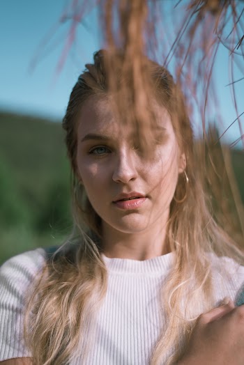 Woman in White Crew-neck Shirt Standing Behind Grass