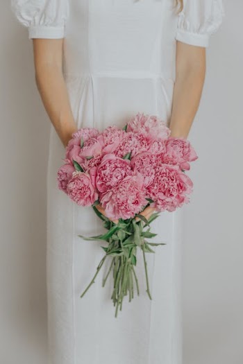 Woman in white dress holding pink flowers · Free Stock Photo