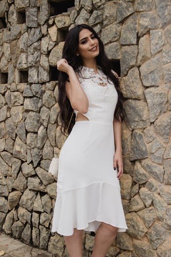 Woman in White Dress Leaning on Brick Wall Posing for Photo