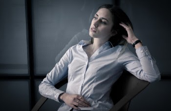 Woman In White Dress Shirt Sitting With Hand Resting On Tummy