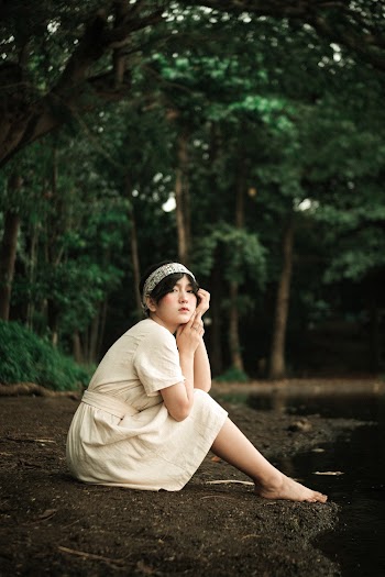 Woman in White Dress Sitting Beside Lake