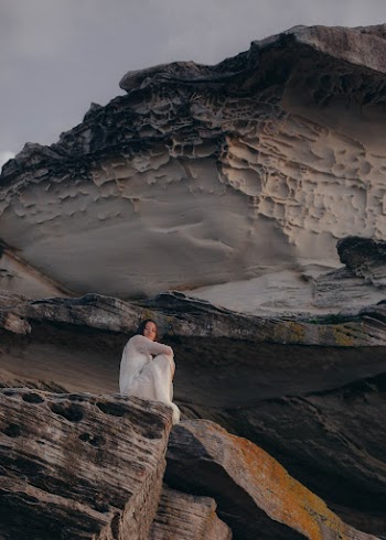 Woman in White Dress Sitting on Top of Rock