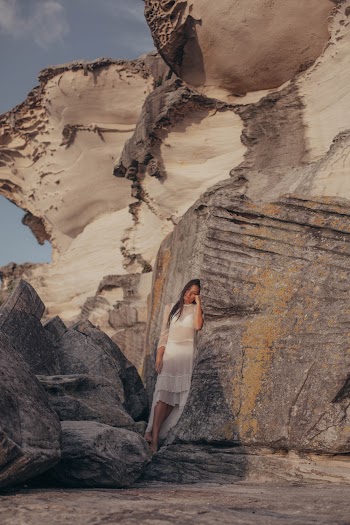 Woman in White Dress Standing on Rock Formation