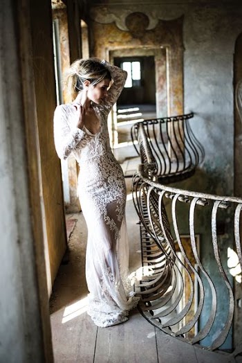 woman in white floral lace scoop-neck long-sleeved dress standing beside rail in concrete building during daytime