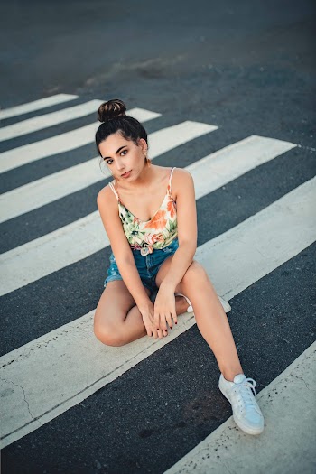 Woman in White, Green, and Orange Floral Spaghetti Strap Top Sitting on Pedestrian Lane
