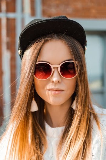 woman in white knit sweater and black fitted cap