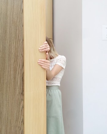 Woman in White Lace Cap-sleeved Top and Green Skirt Hiding Behind Brown Wall
