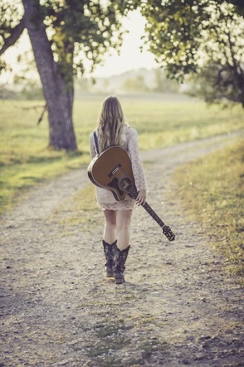 Woman in White Long Sleeve Dress Carrying a Guitar