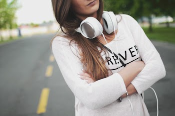 Woman in White Long Sleeve Shirt Standing on Center of Road during Day Time