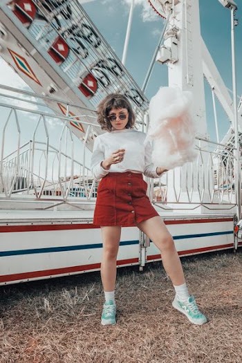 woman in white long-sleeved top holding cotton candy