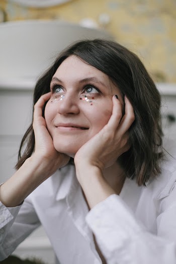 Woman in White Long-sleeved Top Holding Her Face