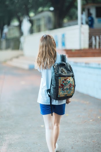 Woman in White Shirt and Blue Shorts Carrying Backpack