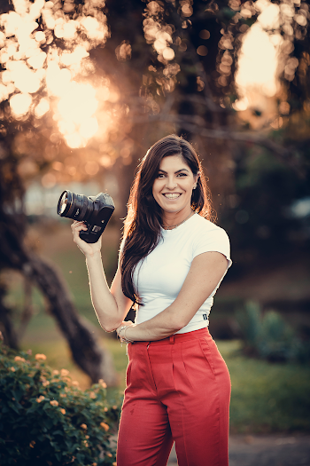 Woman in White Shirt and Red Pants Smiles and Holds Black Dslr Camera