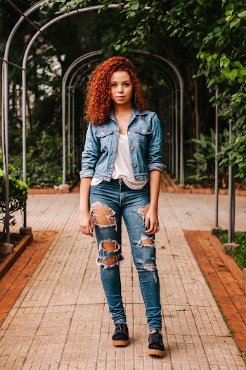 Woman In White Shirt, Blue Denim Jacket And Blue Distressed Denim Jeans Standing On Pathway