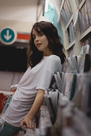 Woman in White Shirt Leaning on Dvd Cases