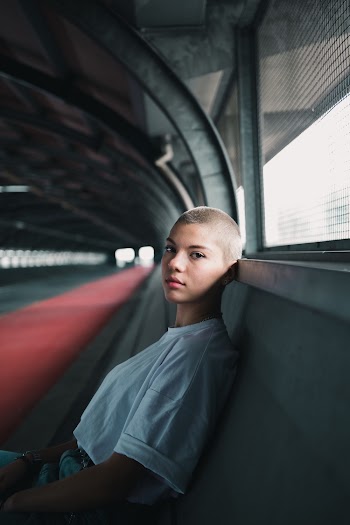 Woman in White Shirt Leaning on Gray Concrete Wall
