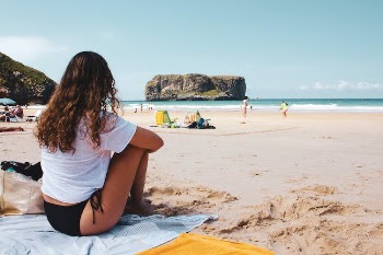 Woman in White Shirt Sitting on a Beach Towel