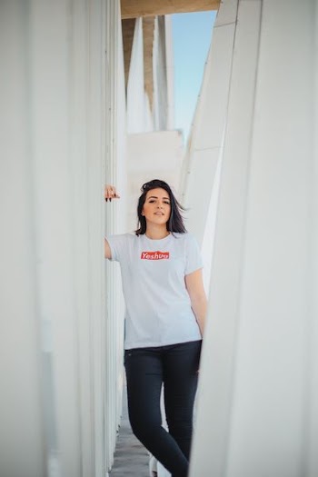 woman in white shirt standing besides white pillar