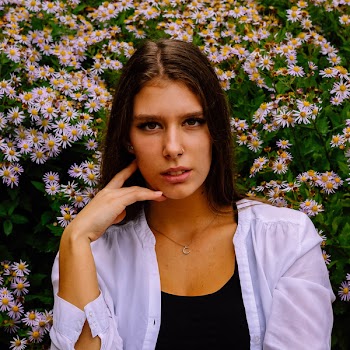 Woman in White Shirt Standing in Front of White Flowers