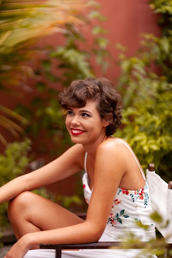 Woman in White Sleeveless Dress Sitting and Smiling Inside Garden