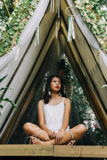 Woman in White Sleeveless Dress Sitting on Bamboo Tree