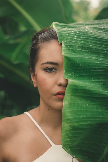 Woman in White Spaghetti Strap Tank Top Looking from Banana Leaves