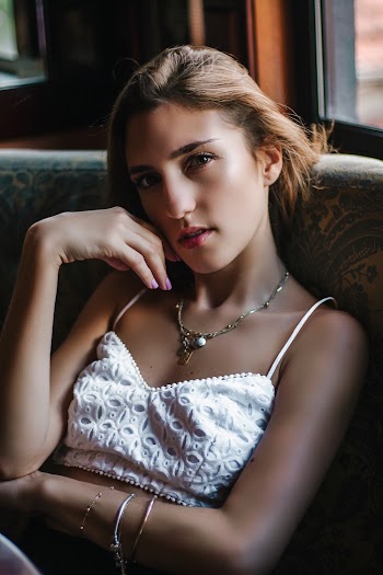 Woman in White Spaghetti Strap Top Sitting on Chair