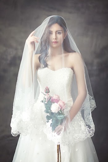 Woman in White Strapless Sweetheart Wedding Dress With Rose Bouquet Covered in White Veil