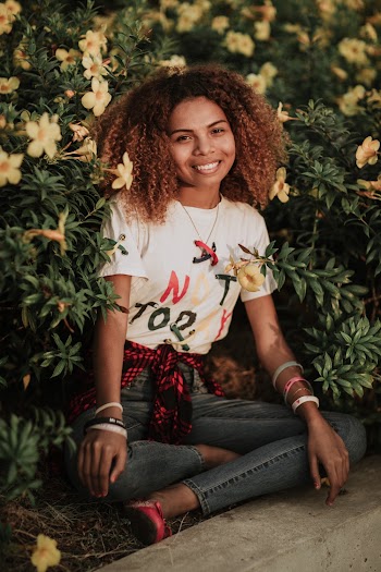 Woman in White T-shirt and Blue Jeans Sitting Near Flowers