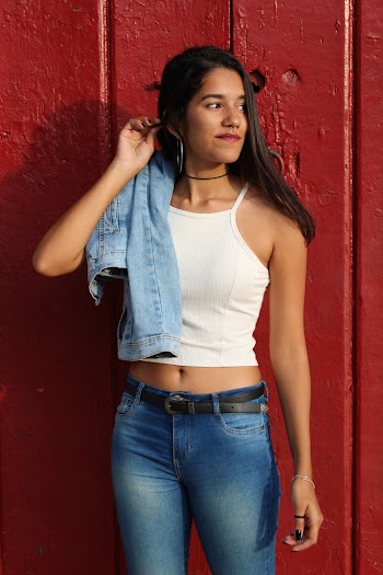 Woman in White Tank Top and Blue Denim Jeans With Blue Denim Jacket Slung over Right Shoulder