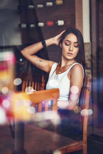 Woman in White Tank Top Sitting Beside Table