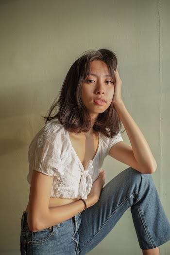 Woman in White Top and Blue Denim Jeans Posing