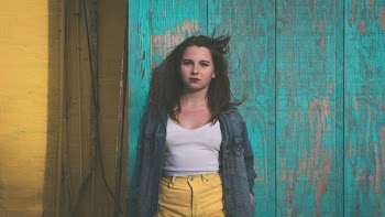 woman in white top leaning on wall
