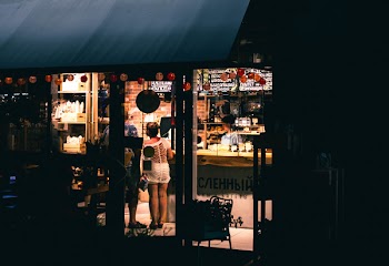 Woman in White Top Mini Dress Standing Near Store Door
