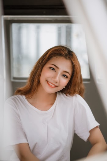 Woman in White Top Near Grey Wall