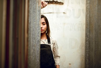 Woman In White Top Standing Behind Wall