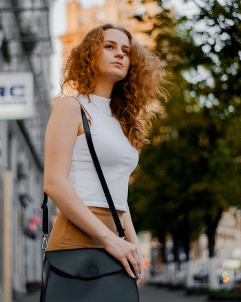 Woman in White Turtleneck Sleeveless Top and Brown Bottoms Holding Black Leather Crossbody Bag Outfit