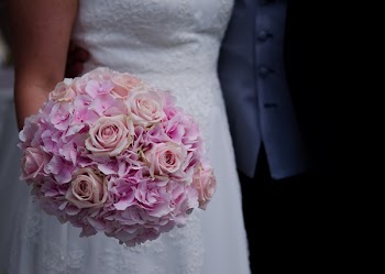 Woman in White Wedding Dress Holding a Bouquet of Flowers
